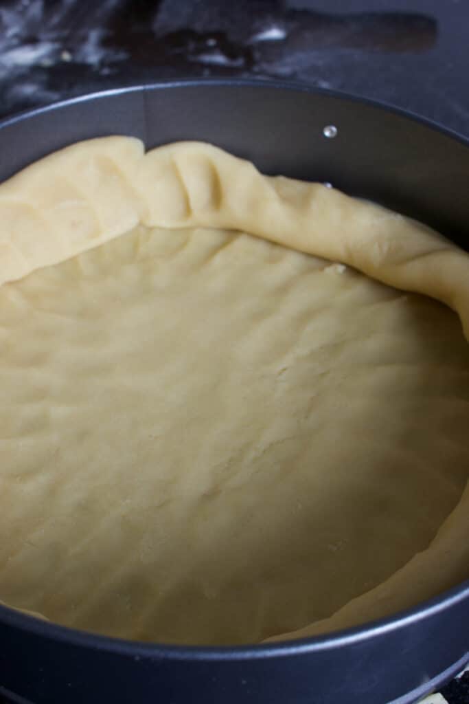 springvorm met appeltaartdeeg op de bodem en een deel langs de rand.