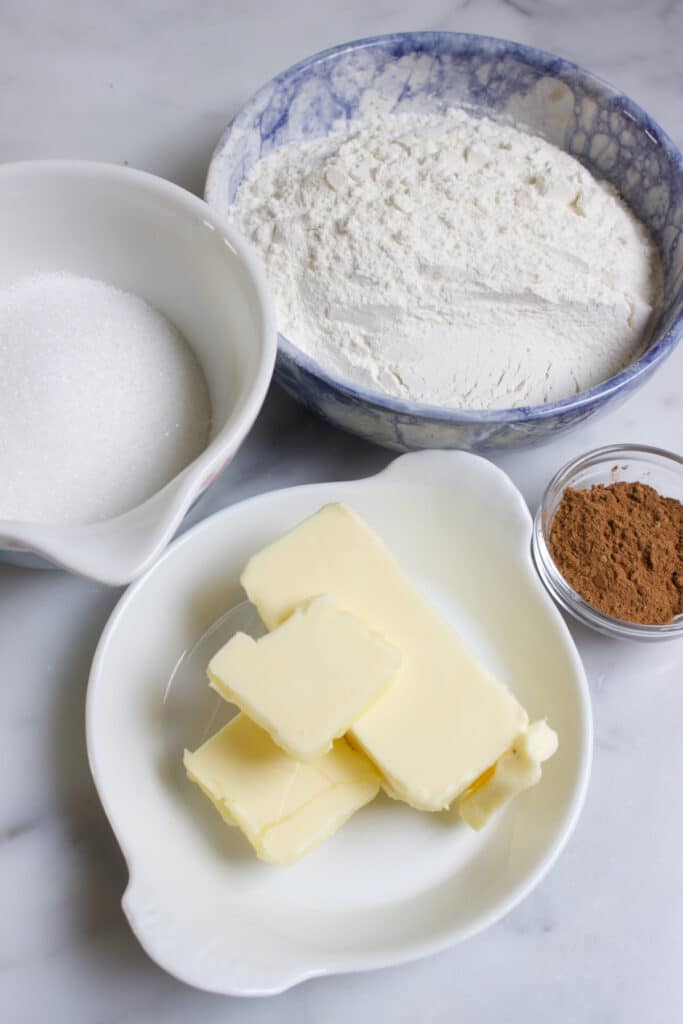 Ingredienten voor de kruimellaag van appeltaart. Kommetjes met bloem, suiker, boter en speculaaskruiden