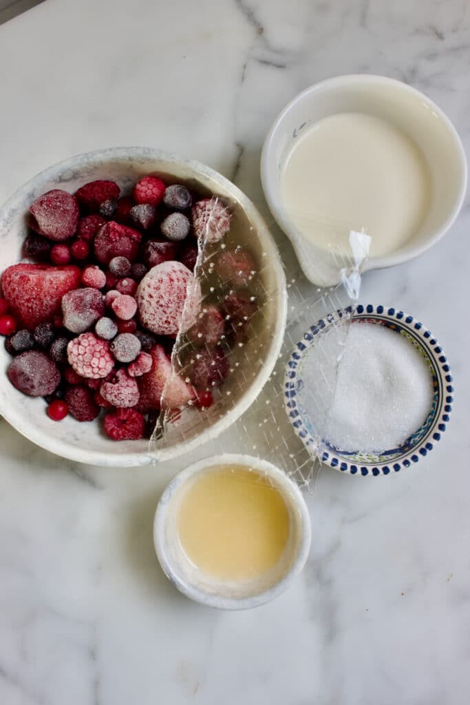 Ingrediënten voor de bavarois in verschillende kommetjes: Diepvries fruit, gelatine, room, suiker en citroensap.