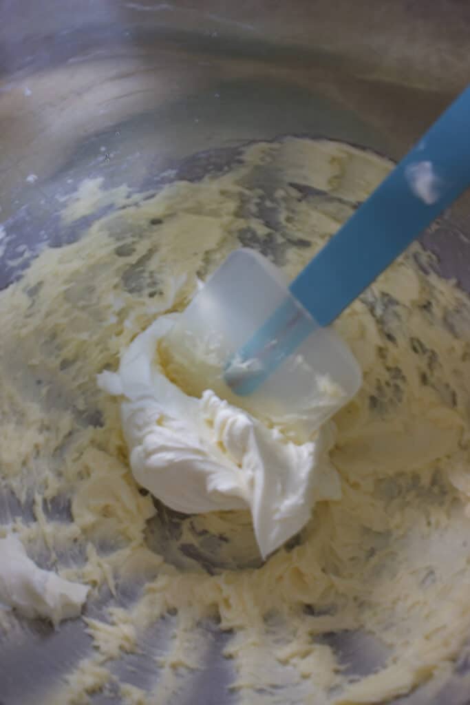 roomkaas toevoegen met een spatel aan een botercreme