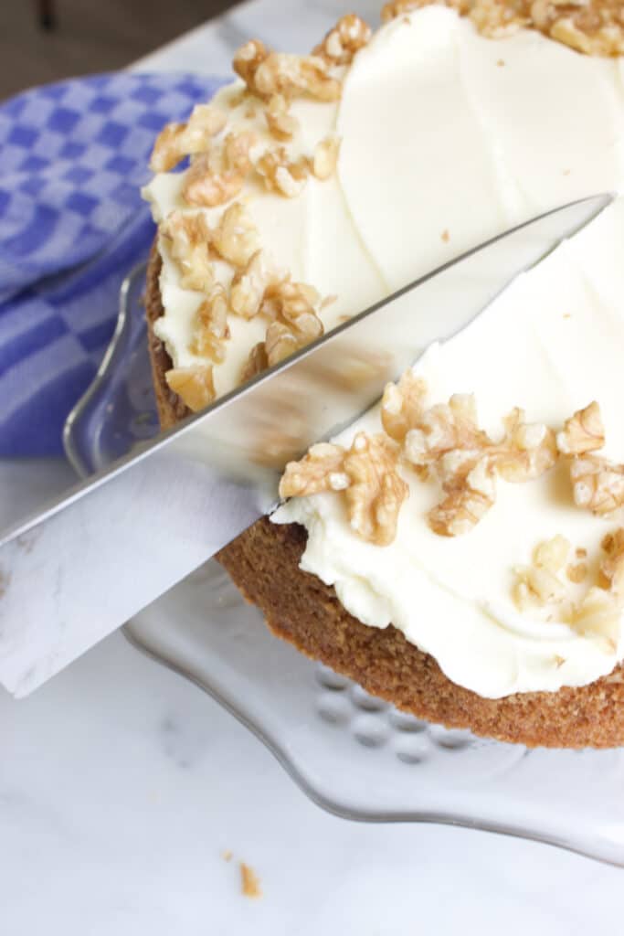 worteltaart met topping doorsnijden met een keukenmes