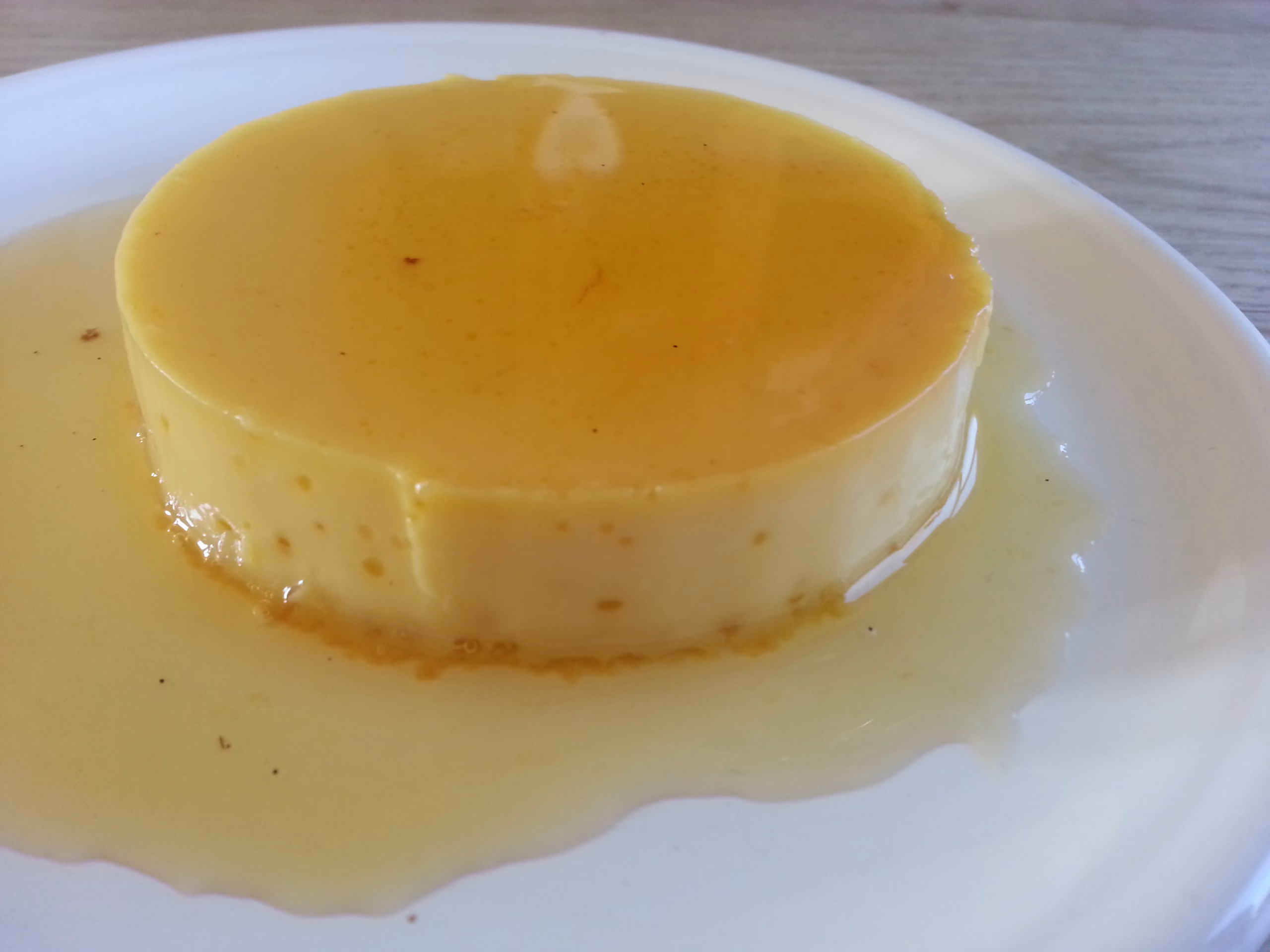 gebakken flan met karamel op een wit bord.