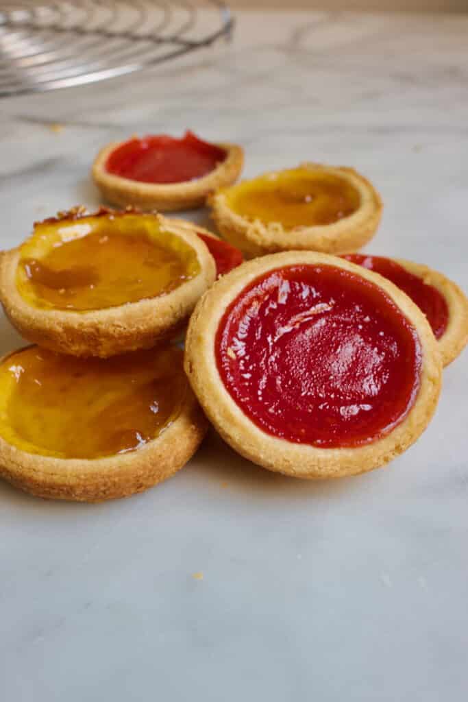 jamkoekjes met aardbeien en abrikozen jam met op de achtergrond een taartrooster