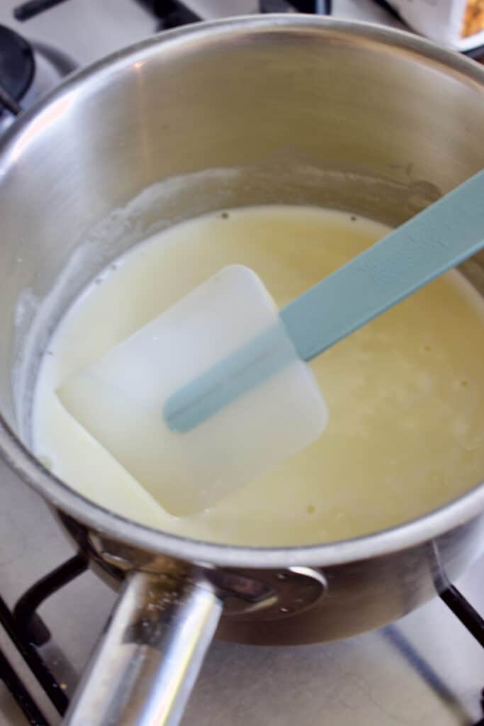 een steelpan met room op het gasfornuis met een blauwe spatel erin