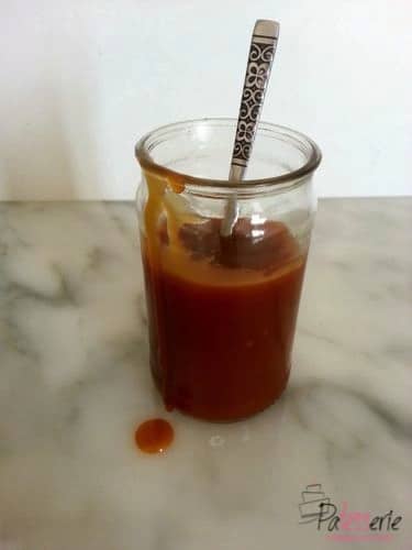 karamelsaus in een glazen potje met een lepel erin