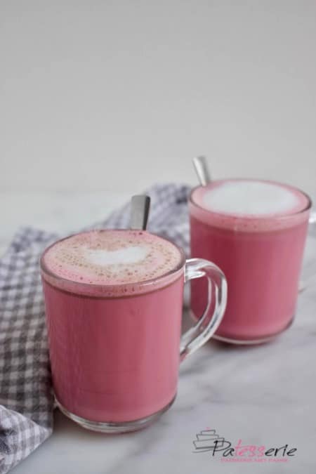 Twee mokken met Red Velvet Latte. Koffie met roze melk en een klein laagje melkschuim. Gemaakt met bietensap voor de roze kleur en chocolade voor de red velvet smaak