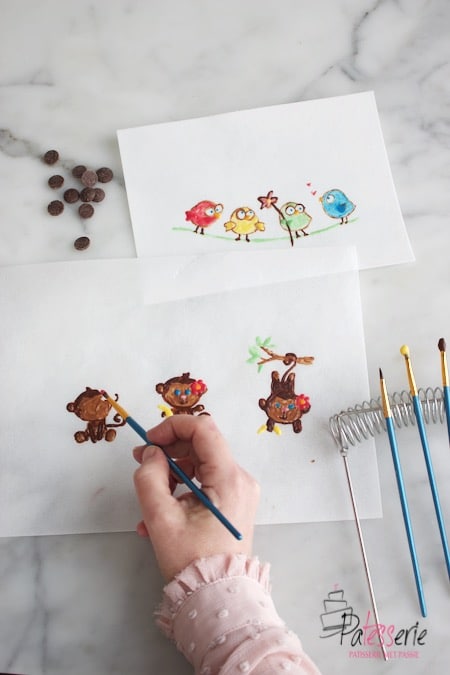 Schilderen met chocolade. Drie kleine aapjes en vogeltjes schilderen met gekleurde chocolade