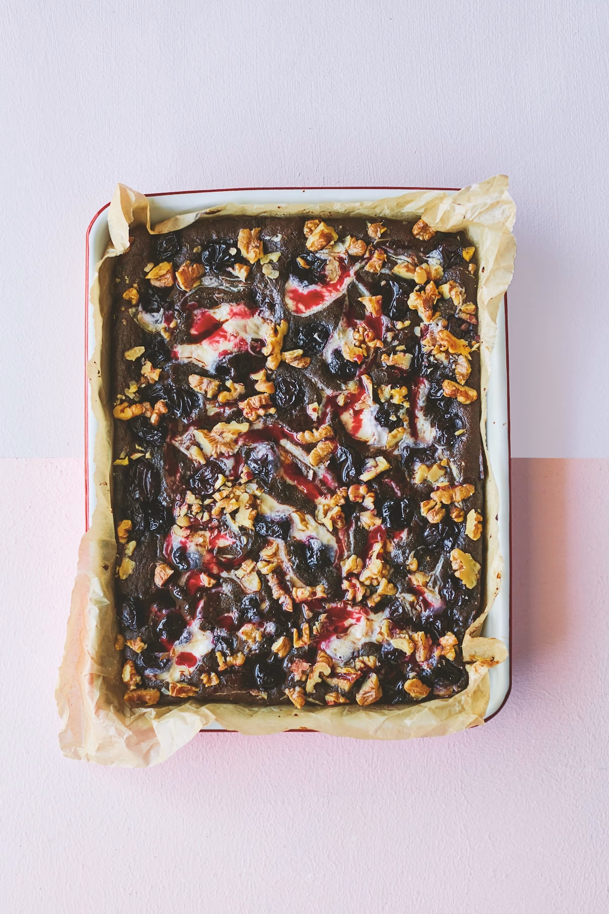 bakplaat met bakpapier en brownies erin met mascarpone, kersen en walnoten