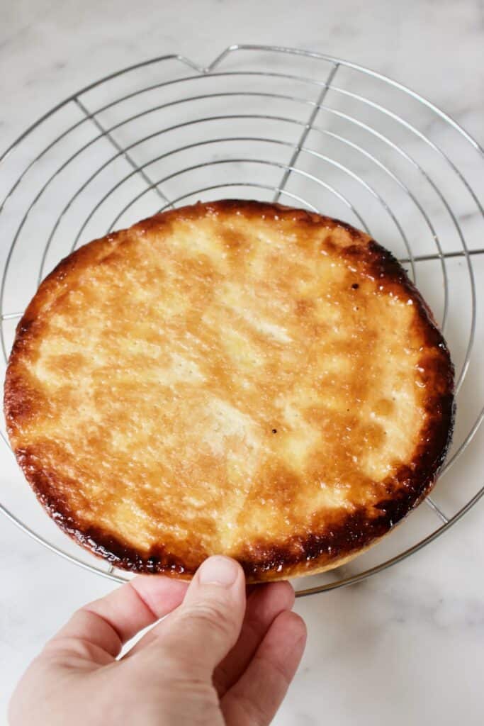 De gebakken onderkant van de bladerdeegbodem van een tarte fine aux pommes (snelle appeltaart) met gekarameliseerde randen. De bodem ligt op een rond taartrooster