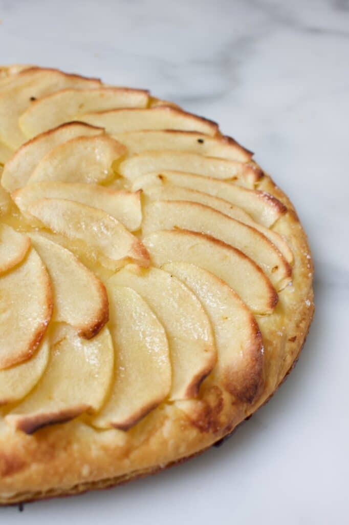 gebakken snelle appeltaart met een bladerdeegbodem en dunne plakjes appel erop in waaiervorm