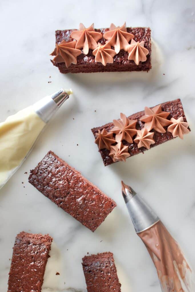 chocoladecake stukjes met cacaojuice ganache in spuitzakken op een marmeren ondergrond
