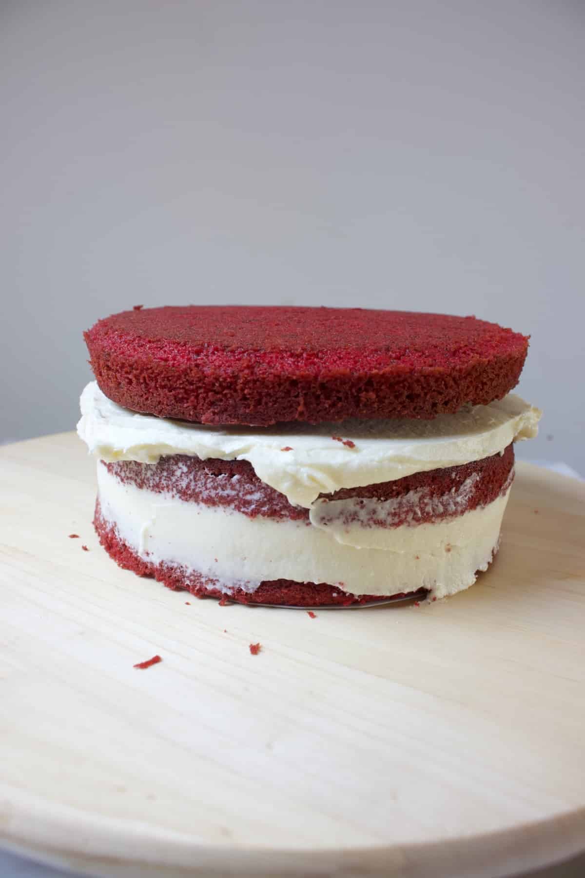 drie lagen red velvet cake die deels gevuld zijn met roomkaas creme voor een red velvet stapeltaart