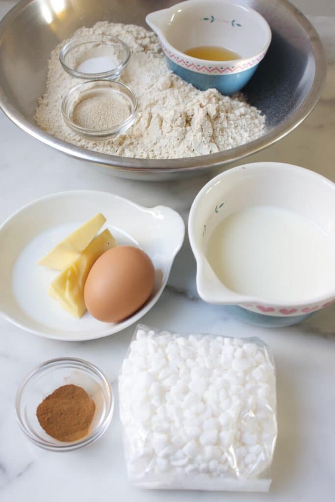 ingredienten voor een fries suikerbrood: bloem, ei, boter, melk, kaneel en een zakje parelsuiker