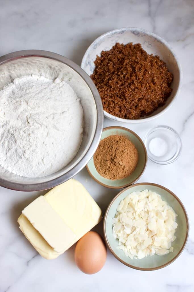 ingredienten voor speculaas boterkoek: bloem, boter, speculaaskruiden, zout, een ei en geschaafde amandelen.