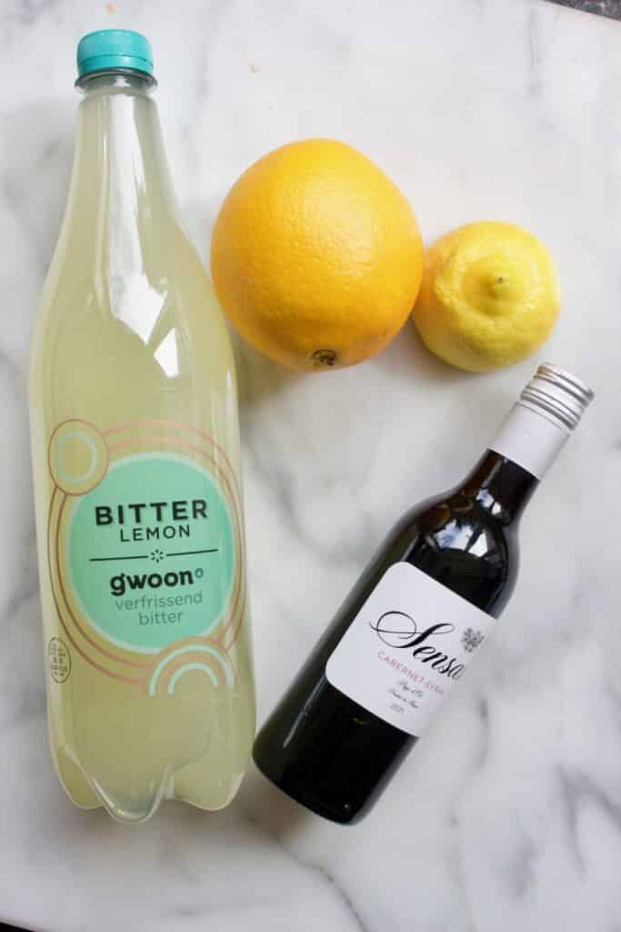 fles bitterlemon, klein flesje rode wijn, een sinaasappel en een citroen om tinto de Verano te maken