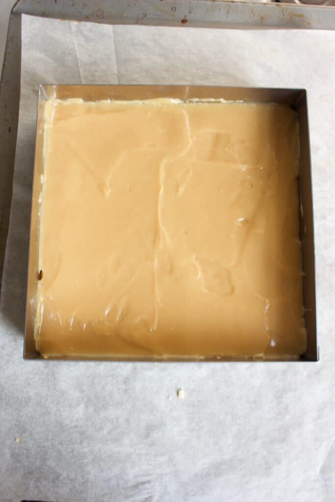 vierkante bakvorm met karamel op een koeklaag