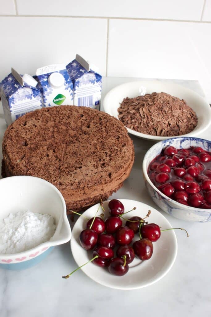 ingredienten voor de Schwarzwalder kirsch taart: slagroom, poedersuiker, chocolade biscuit, kersen, kersen vlaaivulling en chocolade schaafsel