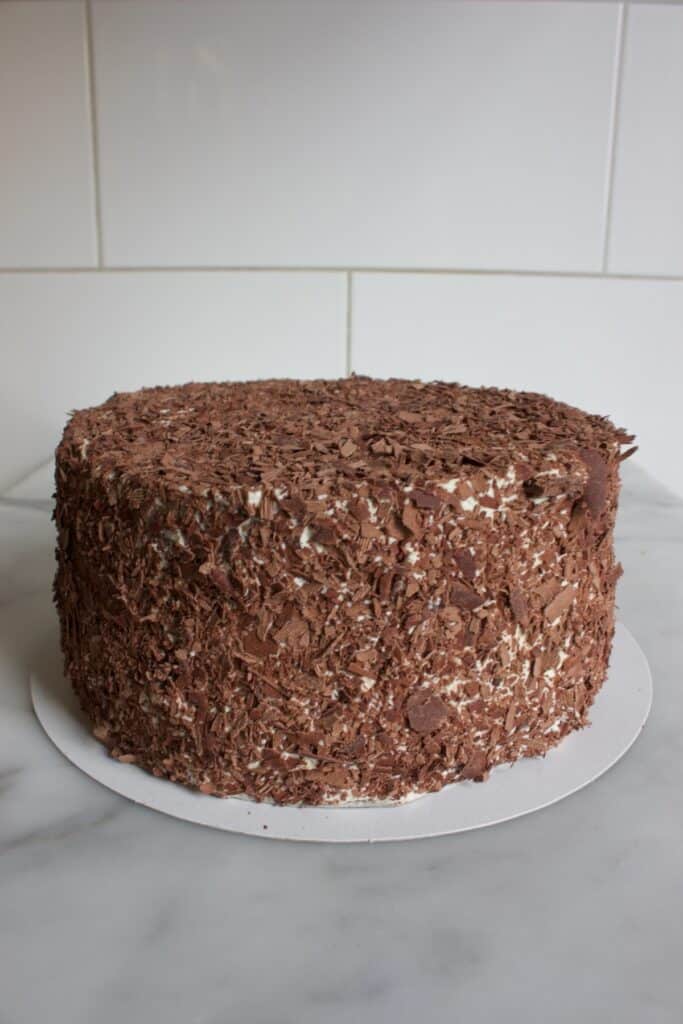 een schwarzwalder kirsch taart afgesmeerd met slagroom en rondom bedekt met chocoladeschaafsel