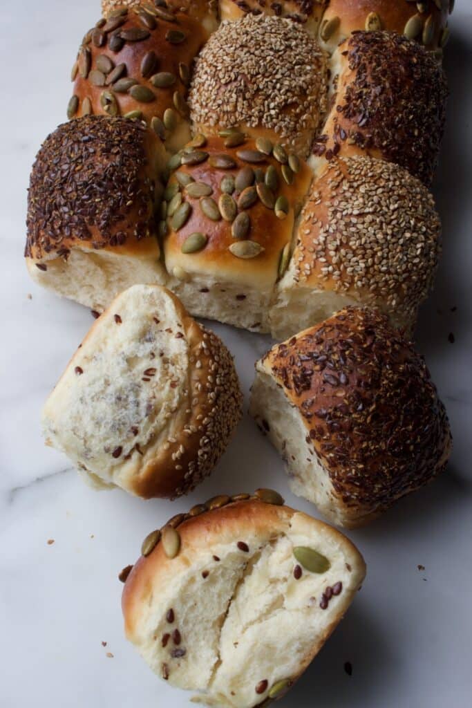 gebakken breekbroodjes met zaden en pitten op de verschillende broodjes (sesamzaad, lijnzaad en pompoenpitten), waarbij er drie broodjes los gemaakt zijn.