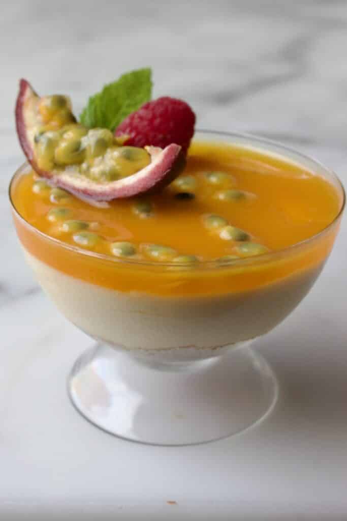 cheesecake in een glas met passievrucht toetjes gedecoreerd met passievrucht, munt en framboos