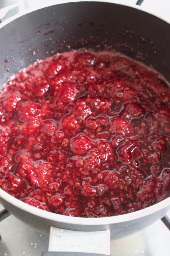 pan met warme frambozen en suiker om frambozensaus te maken