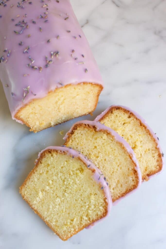 citroencake met lavendel glazuur met daarvoor drie plakjes van deze cake