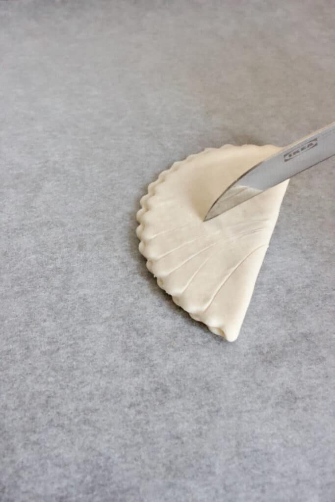 Een halve cirkel bladerdeeg inkepen met een scherp mesje