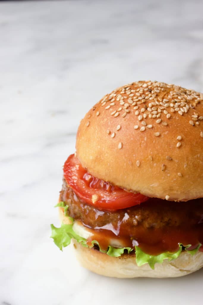 een broodje hamburger met sla, ui, tomaat en barbecuesaus