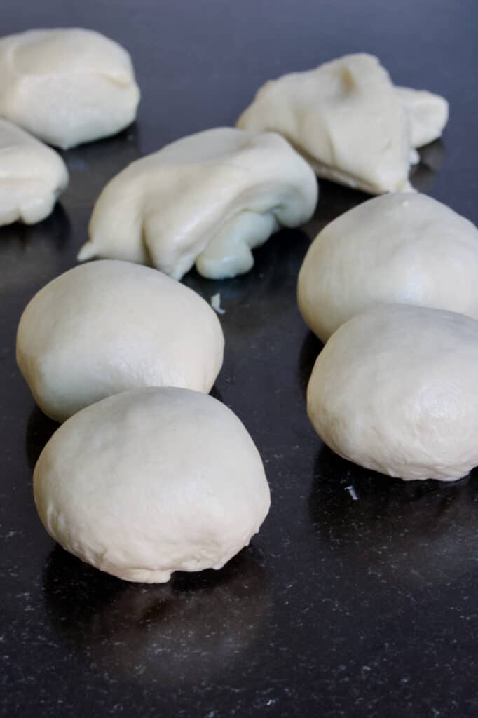 bolletjes deeg die deels al opgebold zijn om broodjes van te bakken