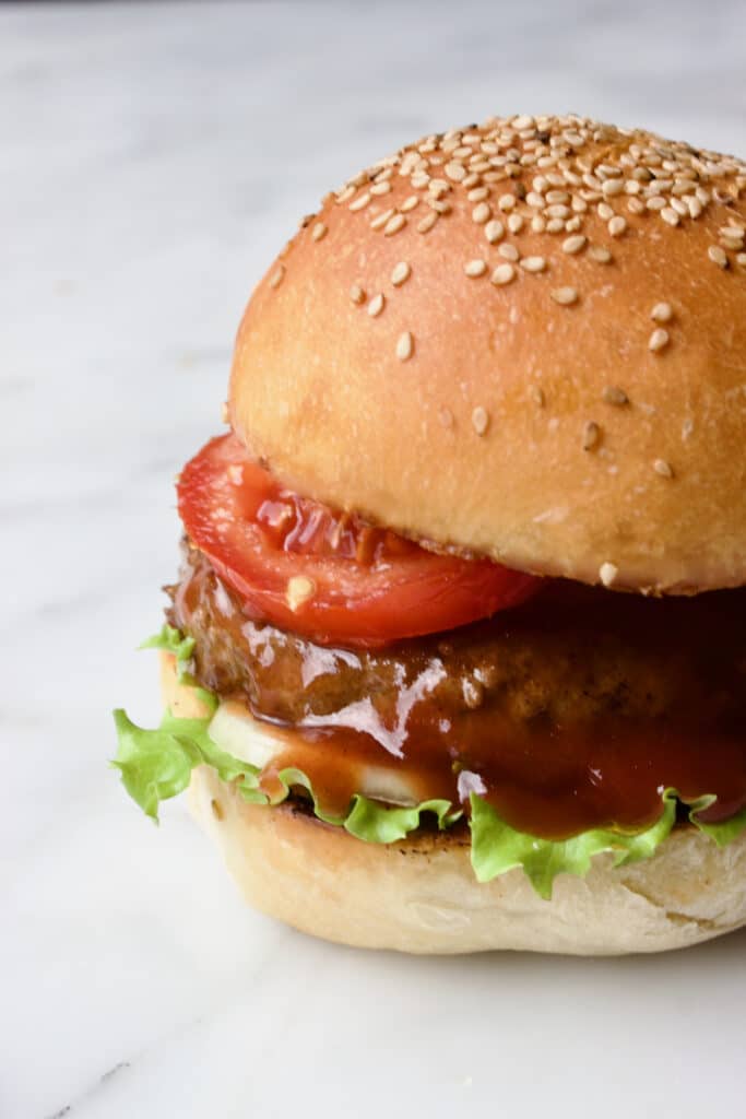 een broodje hamburger met sla, ui, tomaat en barbecuesaus
