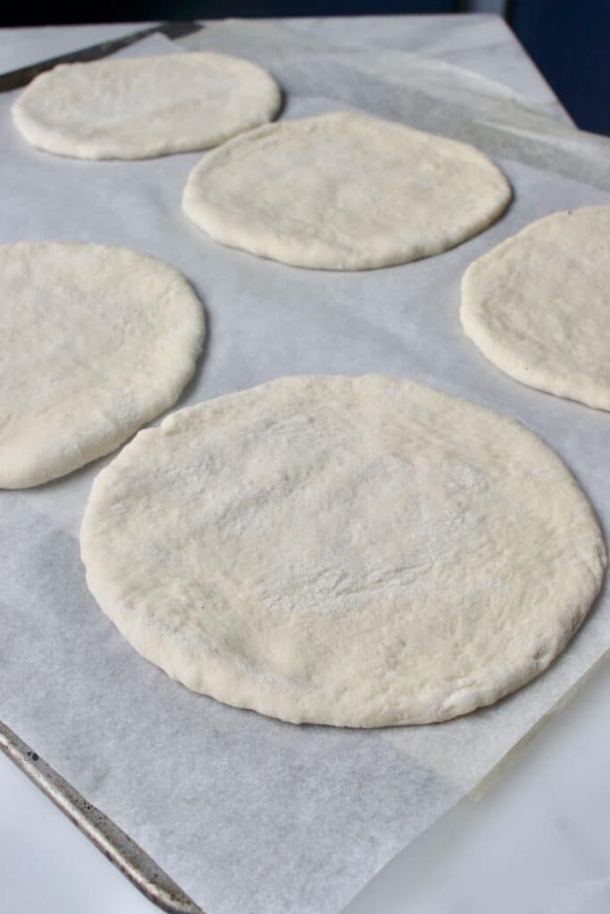 uitgerold deeg voor pitabroodjes op een bakplaat, klaar om de oven in te gaan 