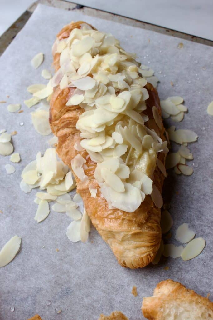 bakplaat met een gebakken croissantje welke bestrooid is met geschaafde amandelen