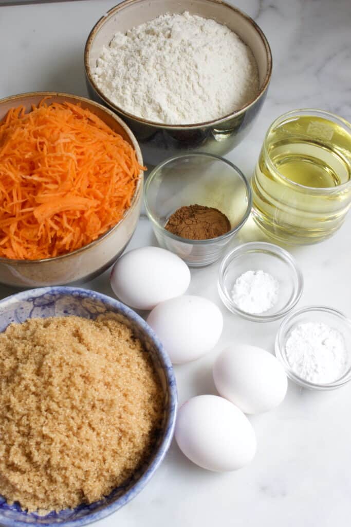 Ingredienten voor carrot cake: basterdsuiker, eieren, olie, bakpoeder, bakingsoda, speculaaskruiden, bloem en geraspte wortel.