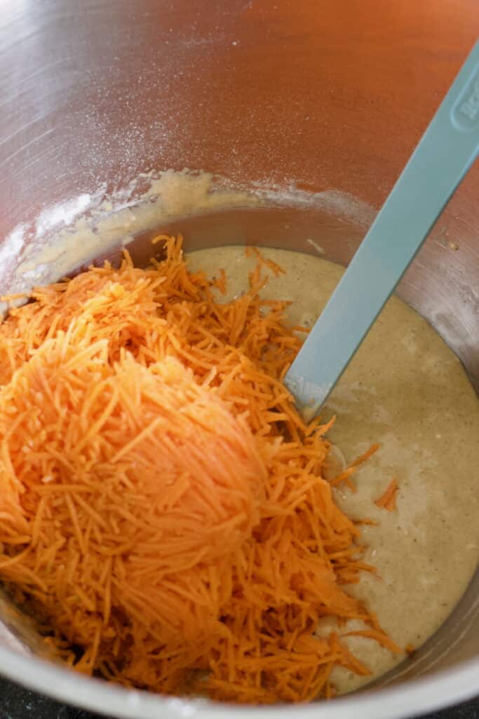 met een spatel geraspte wortel door het beslag voor een carrot cake taart vouwen