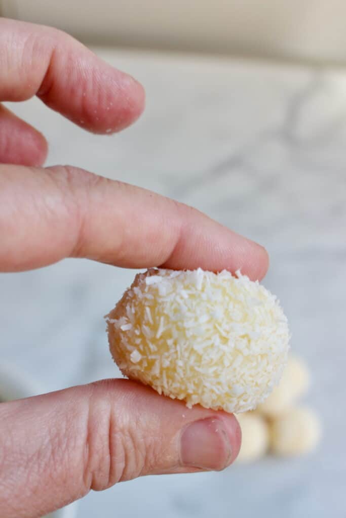 witte kokos brigadeiro tussen duim en wijsvinger