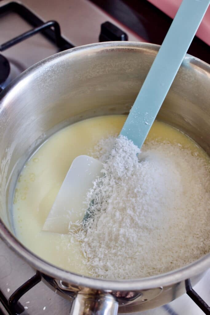 gecondenseerde melk met kokos in een pan doorroeren met een blauwe spatel