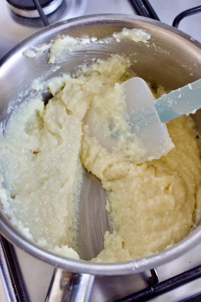 gekookte witte brigadeiros vulling met kokos in een pan, waarbij er met een spatel een streep door getrokken wordt.
