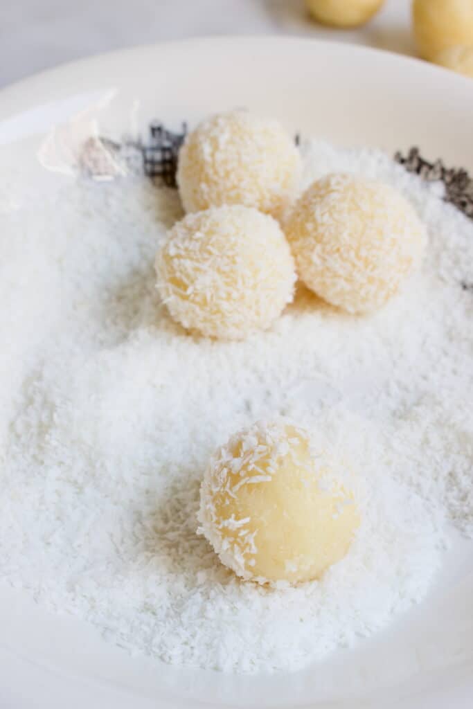witte brigadeiros rollen door een bord gevuld met kokos