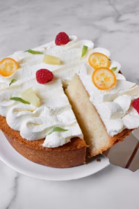 ronde cake met cacaosap erin. Gedecoreerd met slagroom en vers fruit zoals framboos, kumquat en ananas