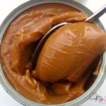 Met een lepel Dulce de leche uit een blikje scheppen